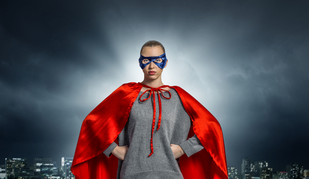 Young confident woman in red cape and maskの写真素材