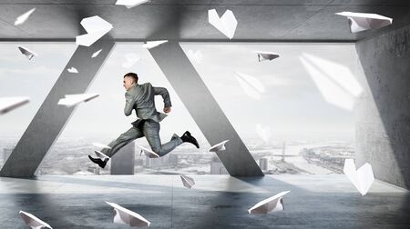 Young dancing businessman in suit in modern interiorの写真素材
