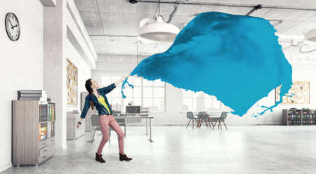 Young woman in office interior pulling blue blank fabric
