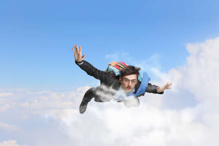 Cheerful businessman with parachute on back flying in skyの写真素材