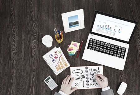 Top view of business workplace and businessman hands writing in notepadの写真素材