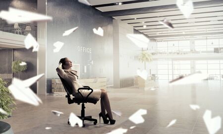 Young relaxed businesswoman sitting relaxed in chair in officeの写真素材