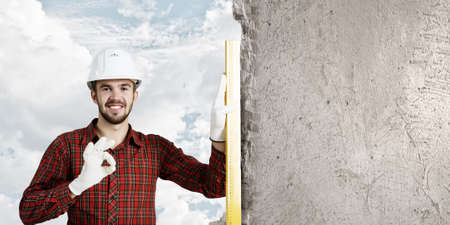 Builder man in checked shirt using measuring level