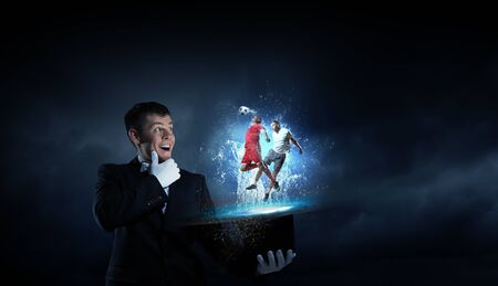 Young cheerful businessman making tricks with magic hat