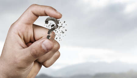 Close view of hand holding question mark between fingersの写真素材