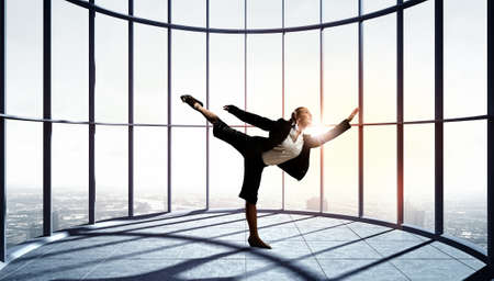 Young dancing businesswoman in suit in modern interior