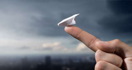 Close view of male hand and paper plane on fingertipの写真素材