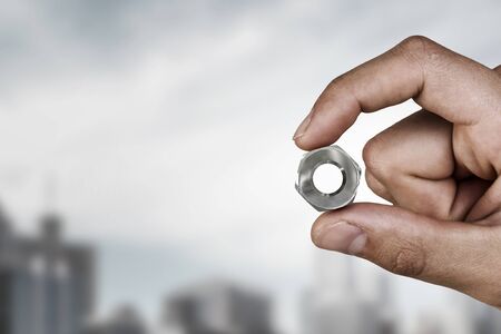 Close view of male hand taking with fingers metal nutの写真素材