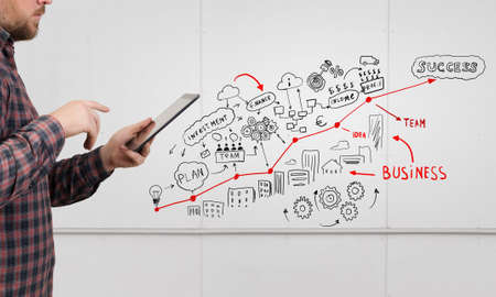 Guy in glasses and checked shirt using tablet pcの写真素材