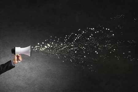 Hand of businessman with megaphone and items flying outの写真素材