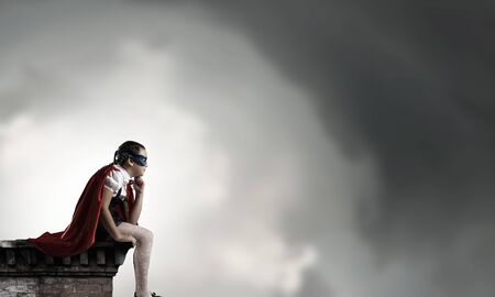 Cute girl of school age sitting on top of buildingの写真素材