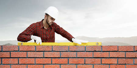 Builder man in checked shirt using measuring levelの写真素材