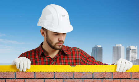 Builder man in checked shirt using measuring level