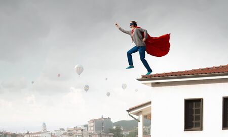 Young determined woman in red cape and maskの写真素材