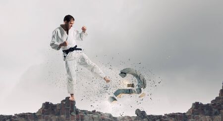 Karate man in jump breaking question markの写真素材