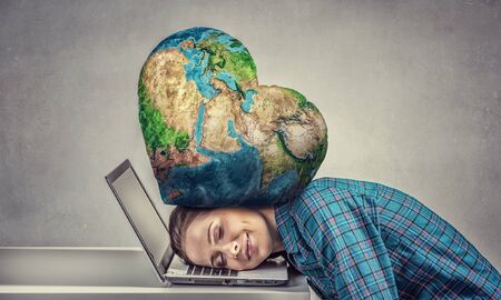 Woman programmer pressed with globe to laptop. Elements of this image are furnished by NASAの写真素材