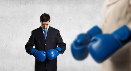 Handsome determined businessman wearing boxing gloves over gray backgroundの写真素材