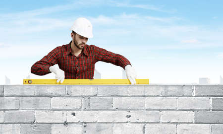 Builder man in checked shirt using measuring level