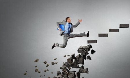 Young businessman walking up collapsing staircase representing success concept