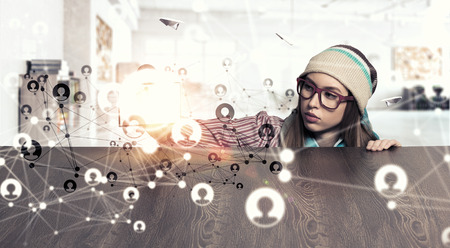 Attractive student girl in red glasses peeping from under tableの写真素材