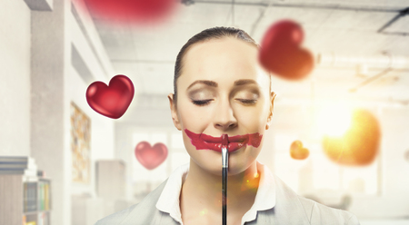 Attractive woman applying red lipstick with brushの写真素材