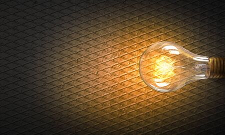 Power and energy concept with glass glowing light bulb on concrete backdropの写真素材