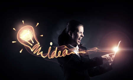 Young emotional businesswoman holding tablet on dark background