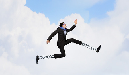 Businessman in suit running with big springs on feet