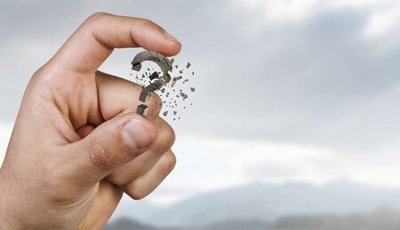 Close view of hand holding question mark between fingers