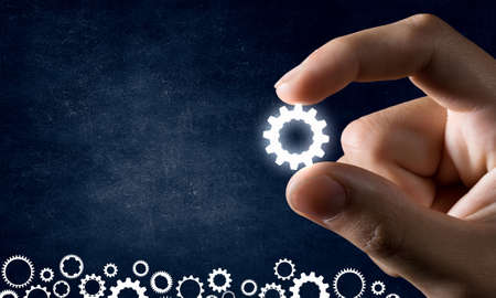 Close view of male hand taking with fingers cogwheelの写真素材