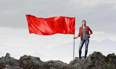 Young woman in red jacket holding waving flagの写真素材