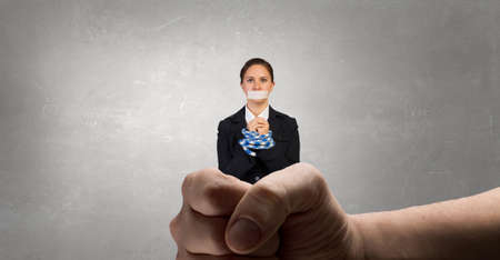 Young businesswoman with tape on mouth and tired handsの写真素材