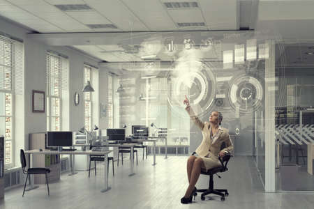 Businesswoman sitting in chair and using virtual interfaceの写真素材