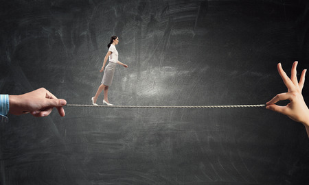 Young businesswoman walking on rope presenting risk and challenge conceptの写真素材