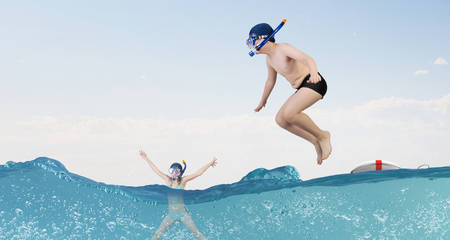Kid boy in diving mask making jump in to waterの写真素材