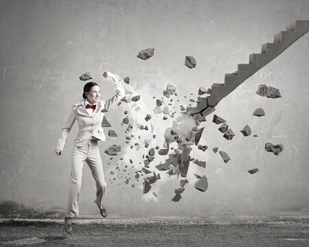 Young businesswoman crashing stone staircase representing success conceptの写真素材