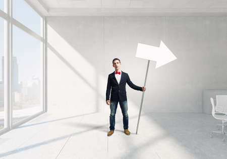 Young man in jacket and bowtie on road holding signの写真素材
