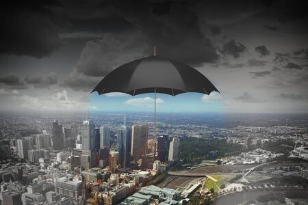 Old black umbrella against rainy sky above cityの写真素材