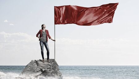 Young woman in red jacket holding waving flagの写真素材