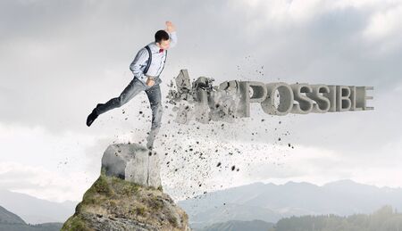 Determined businessman attacking word impossible and breaking letters