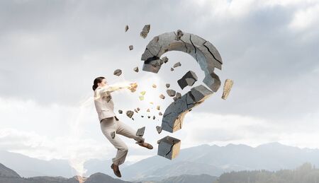 Emotional businesswoman destroying with arm stone question markの写真素材