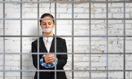 Young businesswoman with tape on mouth and tired handsの写真素材