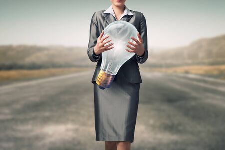 Close view of businesswoman holding in hands glass glowing bulbの写真素材