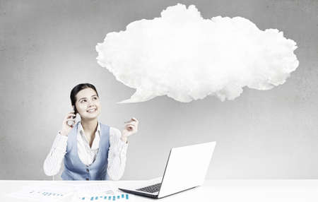 Young attractive businesswoman sitting at table and thinking something overの写真素材