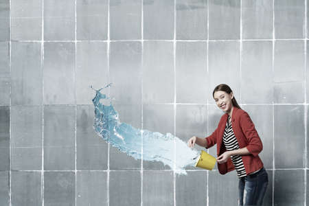Young woman in red jacket holding yellow bucket in handsの写真素材