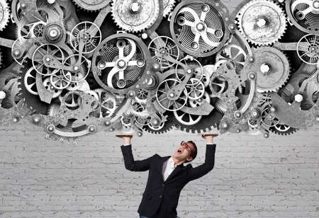 Young student guy in jacket and jeans and gears mechanism as collaboration conceptの写真素材
