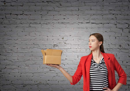 Young woman in red jacket holding carton box in handの写真素材
