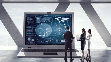Young businesspeople in modern interior and big laptop with graphs and diagrams