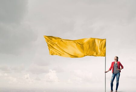 Young woman in red jacket holding waving flagの写真素材