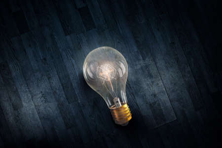 Glowing glass light bulb on wooden background